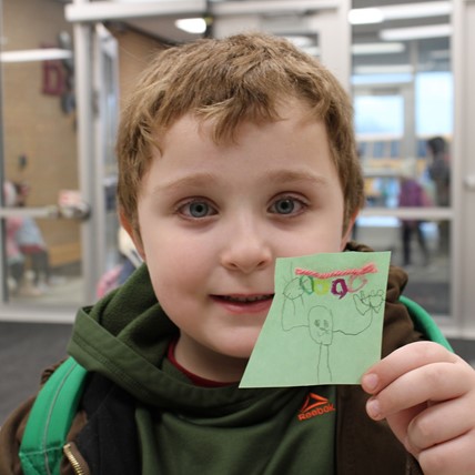 student holds up artwork