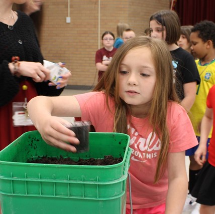 student scooping dirt
